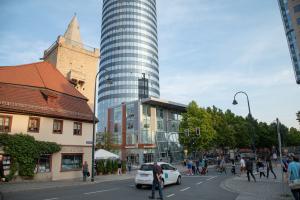 Blick auf den befahrenen und von Fußgängern belaufenen Löbdergraben mit Johannistor und JenTower im Hintergrund