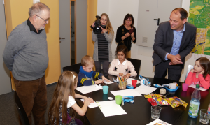 Bild von der Auslosung der Kinderfahrzeuge, 4 Kinder der Kita Schatzinsel im Bild mit Herrn BM Gerlitz, Herrn Comouth (einer der Spender), Frau Grunewald (Kita Schatzinsel). Die Kinder Sitzen am Tisch und öffnen die ausgelosten Umschläge mit den Gewinnern.