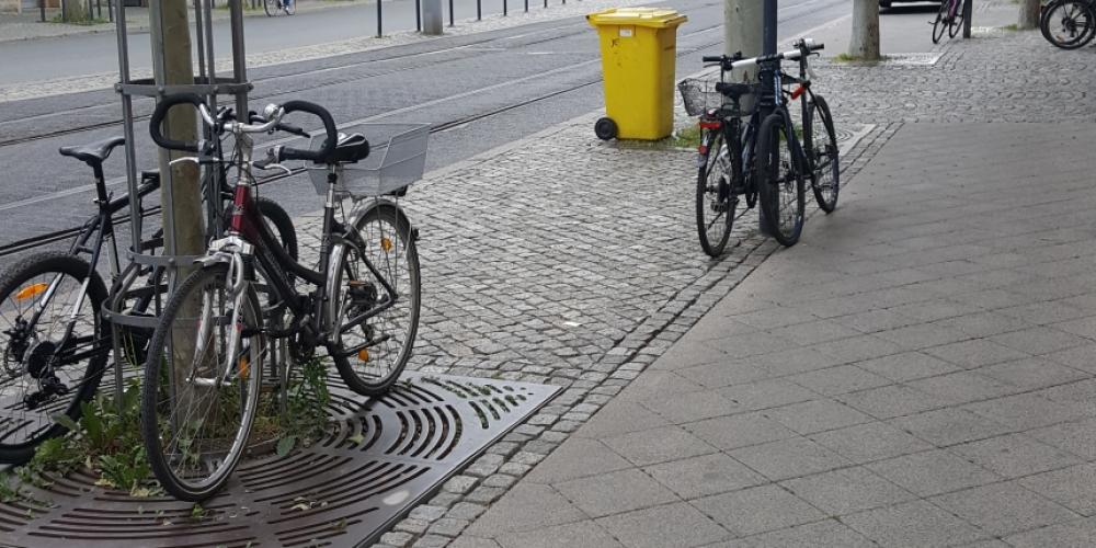 Bild vom Löbdergraben mit Fahrrädern im Vordergrund, dahinter Straßenbahnschienen und Haltestelle