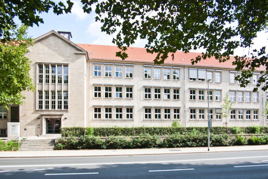 Dienstgebäude Anger 26 - Haupteingang, im Vordergrund Bäume und Straße, blauer Himmel