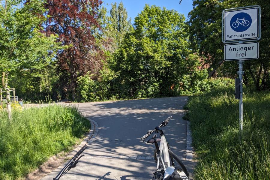 Saaleradweg in Jena zwischen Lobeda West und Gärtnerei Book, Asphaltierter Weg, im Vordergund ein Fahrrad, Beschilderung Fahrradstraße rechts. Im Hintergrund Bäume
